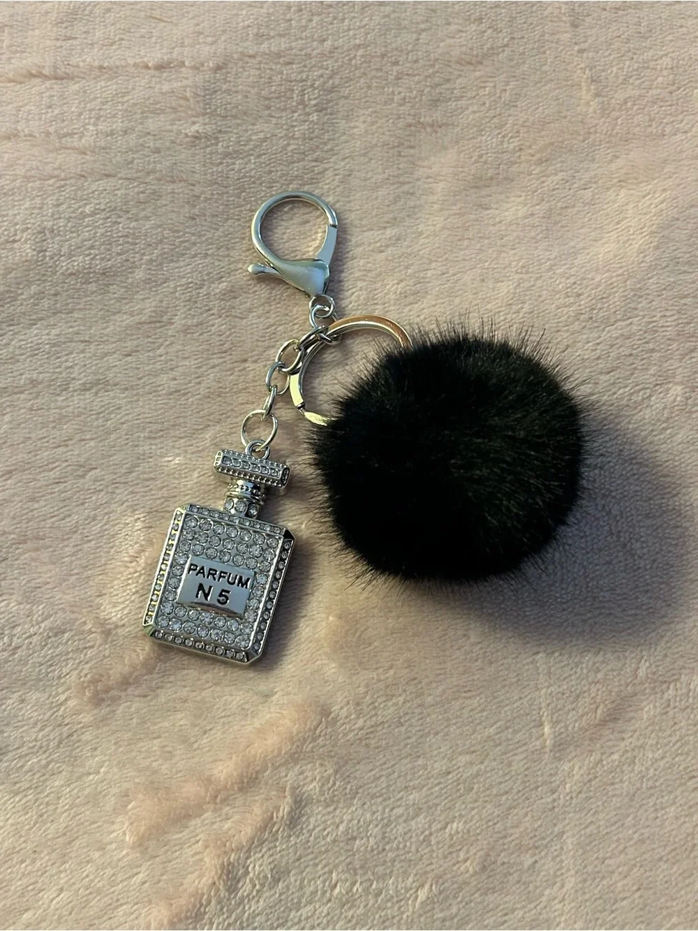 Parfum No. 5 gemstone accented silver bottle with black fuzzy ball purse charm